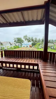a wooden bench on a deck with a view of the beach at Cheriya bungalow Kohyaonoi in Ban Laem Sai