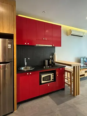 a kitchen with red cabinets and a sink and a table at ReLife NaiHarn Beach by Mill in Rawai Beach