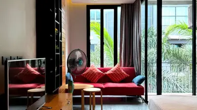 a living room with a red couch in front of a window at ReLife NaiHarn Beach by Mill in Rawai Beach