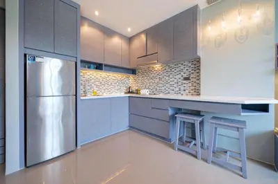 a kitchen with gray cabinets and a stainless steel refrigerator at Relax & Recharge in Modern Comfort at the Hill View Tropics Kamala Suite CTG L607 in Kamala Beach