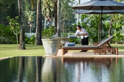a man standing in front of a pool of water with an umbrella at Villa Ananda at Jivana Beach Villas in Pilai Beach