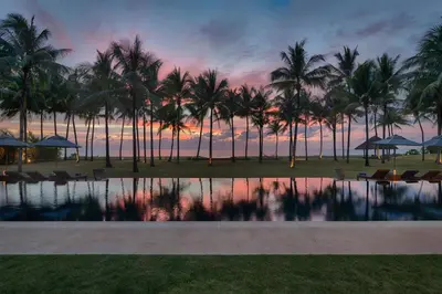 a sunset at a resort with palm trees and a pool at Villa Ananda at Jivana Beach Villas in Pilai Beach
