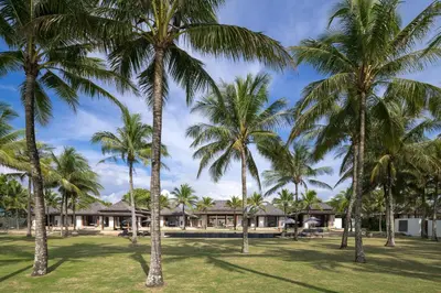 a group of palm trees in front of a house at Villa Ananda at Jivana Beach Villas in Pilai Beach