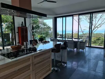 a kitchen with a counter and a table with chairs at Krabi Glass House Sea View Villa in Tab Kaek Beach