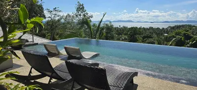 a swimming pool with chairs and a table and water at Krabi Glass House Sea View Villa in Tab Kaek Beach