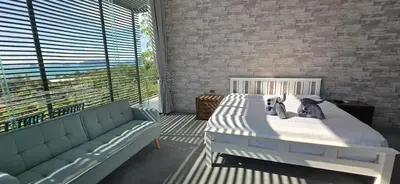 a bedroom with a bed and a couch and a large window at Krabi Glass House Sea View Villa in Tab Kaek Beach