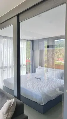 a large bed in a room with a glass window at AdWords Mountain View CityGate Kamala in Phuket Town