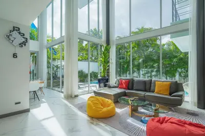 a living room with a couch and tables and windows at Spacious 4BR Pool Villa at Grand View in Bangtao in Bang Tao Beach