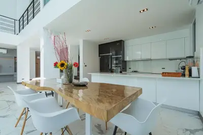 a kitchen with a wooden table and white chairs at Spacious 4BR Pool Villa at Grand View in Bangtao in Bang Tao Beach