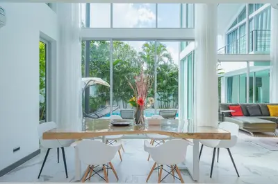 a dining room with a table and white chairs at Spacious 4BR Pool Villa at Grand View in Bangtao in Bang Tao Beach