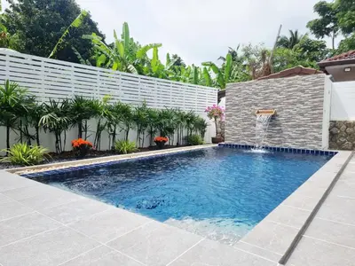 a swimming pool with a waterfall in a backyard at Sanook villas Nai Harn beach in Rawai Beach