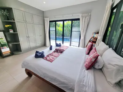 a bedroom with a white bed with pillows on it at Sanook villas Nai Harn beach in Rawai Beach