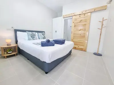 a bedroom with a large bed and a wooden door at Sanook villas Nai Harn beach in Rawai Beach
