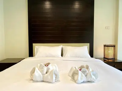 two white towels sitting on top of a bed at Lucky Residence Patong in Patong Beach