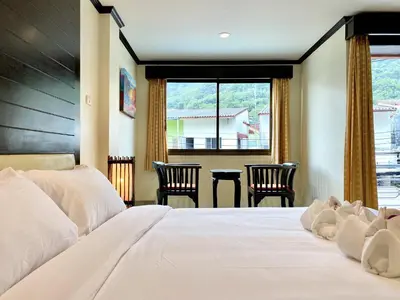 a bedroom with a large bed with chairs and a window at Lucky Residence Patong in Patong Beach