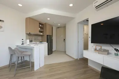 a white kitchen with a bar and a tv at Sky Park condo 1 bedroom in Laguna Phuket