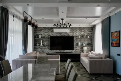 a living room with a brick wall and a television at Phuket Villa Sofia in Ban Phak Chit