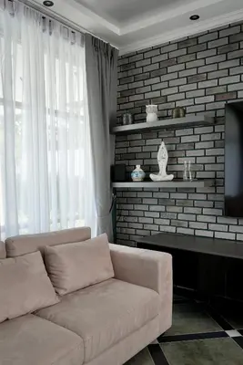 a living room with a couch and a brick wall at Phuket Villa Sofia in Ban Phak Chit