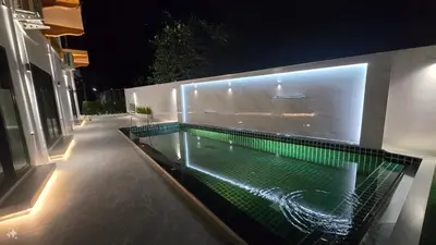 a swimming pool with green lights on the side of a building at Smile Boutique at Saiyuan in Rawai Beach