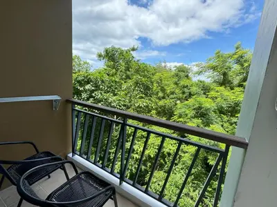 a balcony with two chairs and a view of trees at Cozy apartment at peaceful Rawai Condo in Rawai Beach