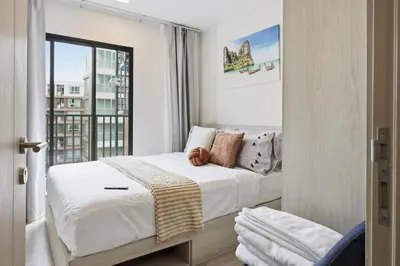 a bedroom with a bed with white sheets and a window at Dcondo Reef Modern Condos 1&2 Bedrooms in Kathu