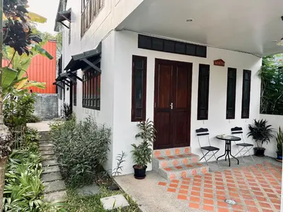 a white house with a wooden door and a table at 103-25 Kathu Waterfall in Phuket Town
