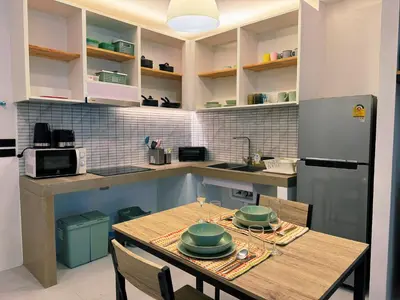 a kitchen with a table with chairs and a refrigerator at Ground Floor Zen Space Kamala in Kamala Beach