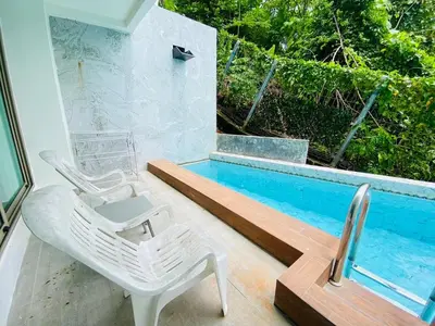 a white chair sitting next to a swimming pool at Oceana Kamala in Kamala Beach