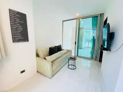 a living room with a couch and a tv at Oceana Kamala in Kamala Beach