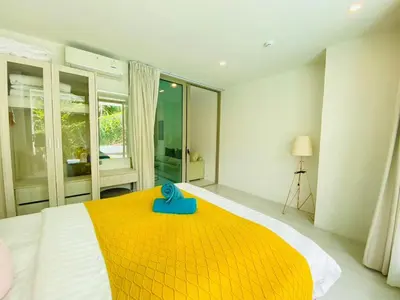 a bedroom with a large bed with a blue item on it at Oceana Kamala in Kamala Beach