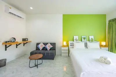 a bedroom with two beds and a green wall at Karon Hotel at 22 in Karon Beach