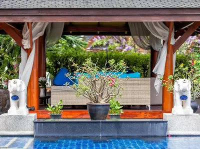 a house with a swimming pool with plants and a porch at Baan Surin Sawan in Surin Beach