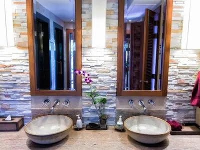 two sinks in a bathroom with two mirrors at Baan Surin Sawan in Surin Beach