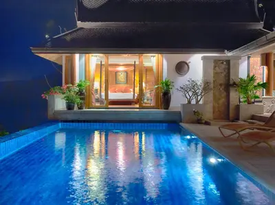 a swimming pool in a house with a bed in the background at Baan Surin Sawan in Surin Beach
