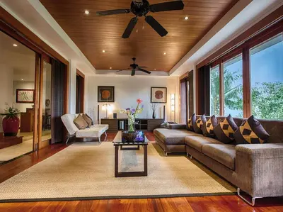a living room with a couch and a ceiling fan at Baan Surin Sawan in Surin Beach
