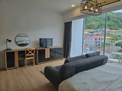 a living room with a couch and a tv and a window at The Olive Studio Room at Chic Condominium in Karon Beach