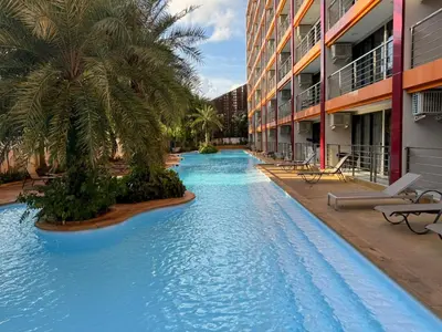 a swimming pool in the middle of a building with palm trees at Apartment Mai Khao Beach in Mai Khao Beach