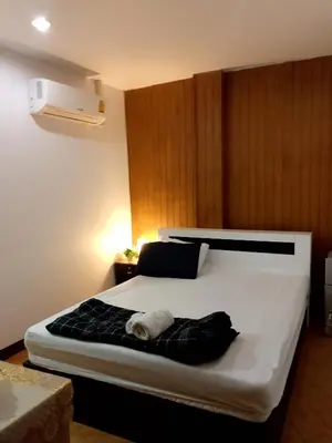 a bedroom with a large white bed with a black blanket at Lucky Guest house in Karon Beach