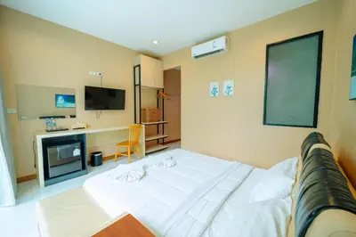 a bedroom with a white bed and a flat screen tv at Rich Pool Villa Phang Nga in Khok Kloi