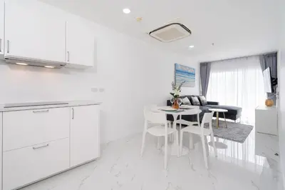 a kitchen with white cabinets and a table and chairs at Patong Tower Brand 1-Bedroom apartment mountain view , Near Beach in Patong Beach