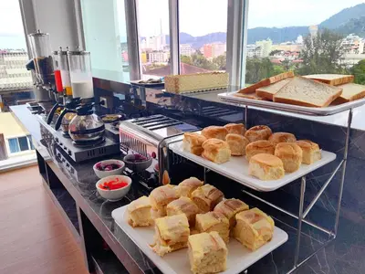 a buffet with several trays of bread and pastries at Meet Holiday International Hotel-Patong \u666e\u5409\u5c9b\u76f8\u9047\u56fd\u9645\u5ea6\u5047\u9152\u5e97-\u82ad\u4e1c\u5e97 in Patong Beach
