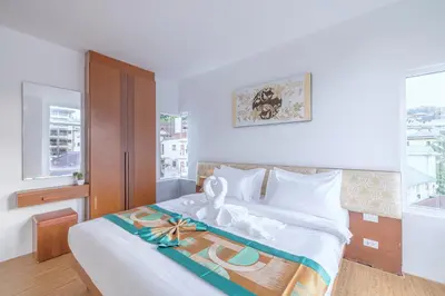 a bedroom with a bed with white sheets and a window at Meet Holiday International Hotel-Patong \u666e\u5409\u5c9b\u76f8\u9047\u56fd\u9645\u5ea6\u5047\u9152\u5e97-\u82ad\u4e1c\u5e97 in Patong Beach