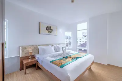 a white bedroom with a bed and a window at Meet Holiday International Hotel-Patong \u666e\u5409\u5c9b\u76f8\u9047\u56fd\u9645\u5ea6\u5047\u9152\u5e97-\u82ad\u4e1c\u5e97 in Patong Beach