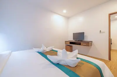a bedroom with a bed with white pillows and a tv at Meet Holiday International Hotel-Patong \u666e\u5409\u5c9b\u76f8\u9047\u56fd\u9645\u5ea6\u5047\u9152\u5e97-\u82ad\u4e1c\u5e97 in Patong Beach