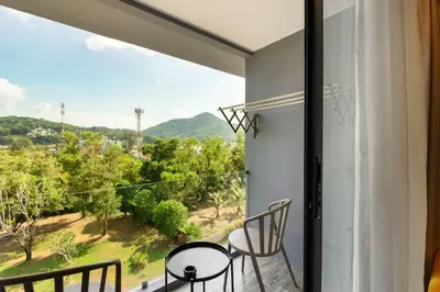 a room with a balcony with a view of trees at Kamala CityGate Apartments in Kamala Beach