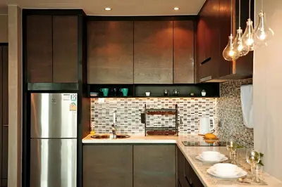 a kitchen with wooden cabinets and a stainless steel refrigerator at Kamala CityGate Apartments in Kamala Beach