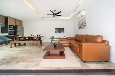 a living room with a brown leather couch and a table at \u5bbd\u655e\u8212\u9002 \u90a6\u6d9b\u6d77\u6ee9Laguna\u9644\u8fd1 \u4e09\u5367\u5ba4\u79c1\u4eba\u6cf3\u6c60\u522b\u5885 in Phuket Town