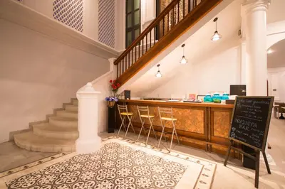 a restaurant with a bar and a counter with chairs at Little Nyonya Hotel in Phuket Town