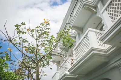 a white building with a tree in front of it at Little Nyonya Hotel in Phuket Town
