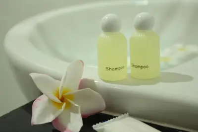two bottles of shampoo and a flower on a table at Bida Daree Resort in Ao Nang Beach